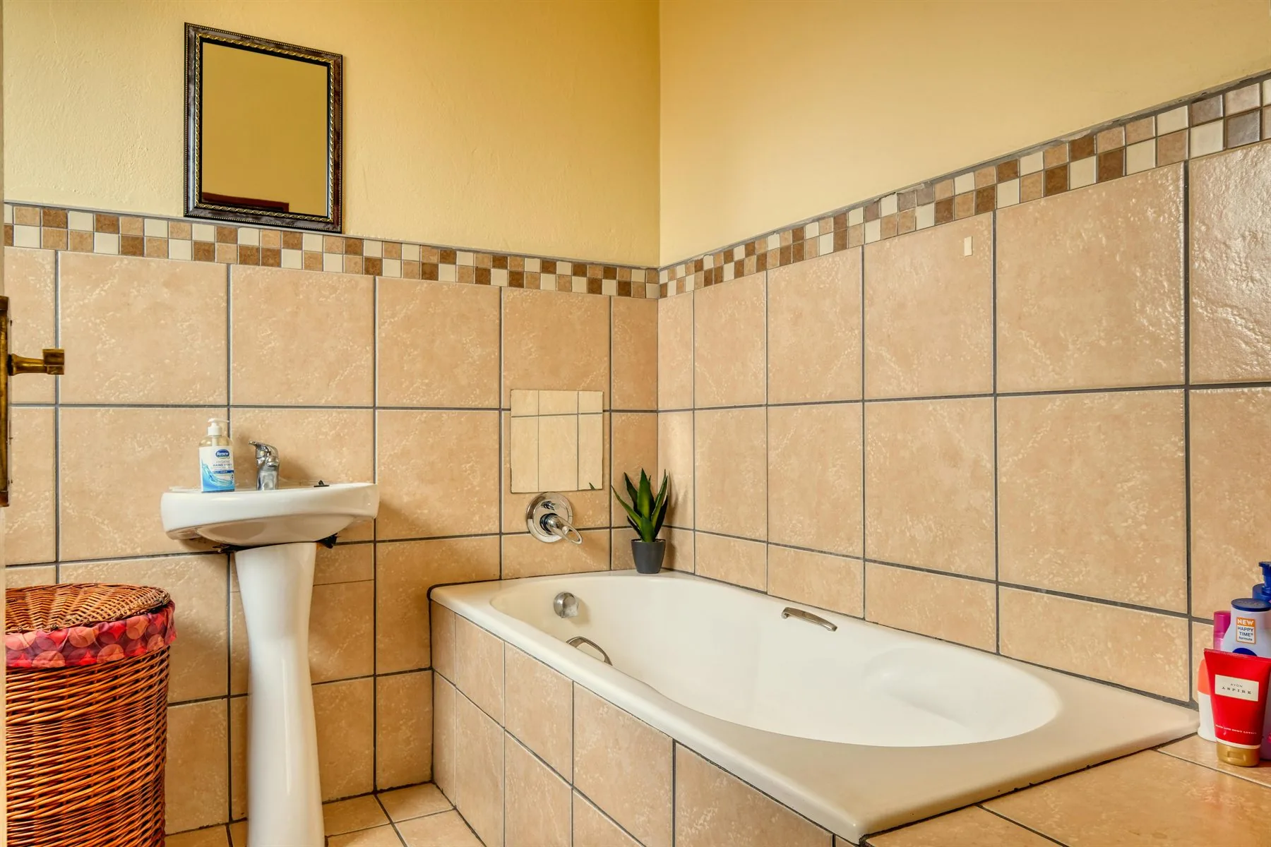 Bathroom with sandy tan tile, warm walls, and a tub with a simple natural palette