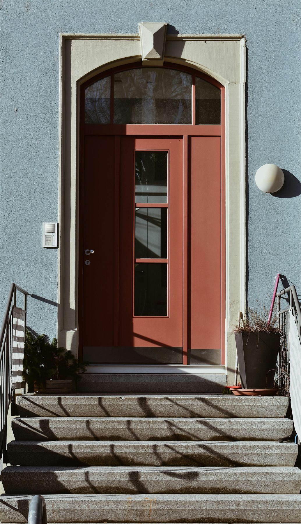 Terracotta front door with steps and a light exterior wall