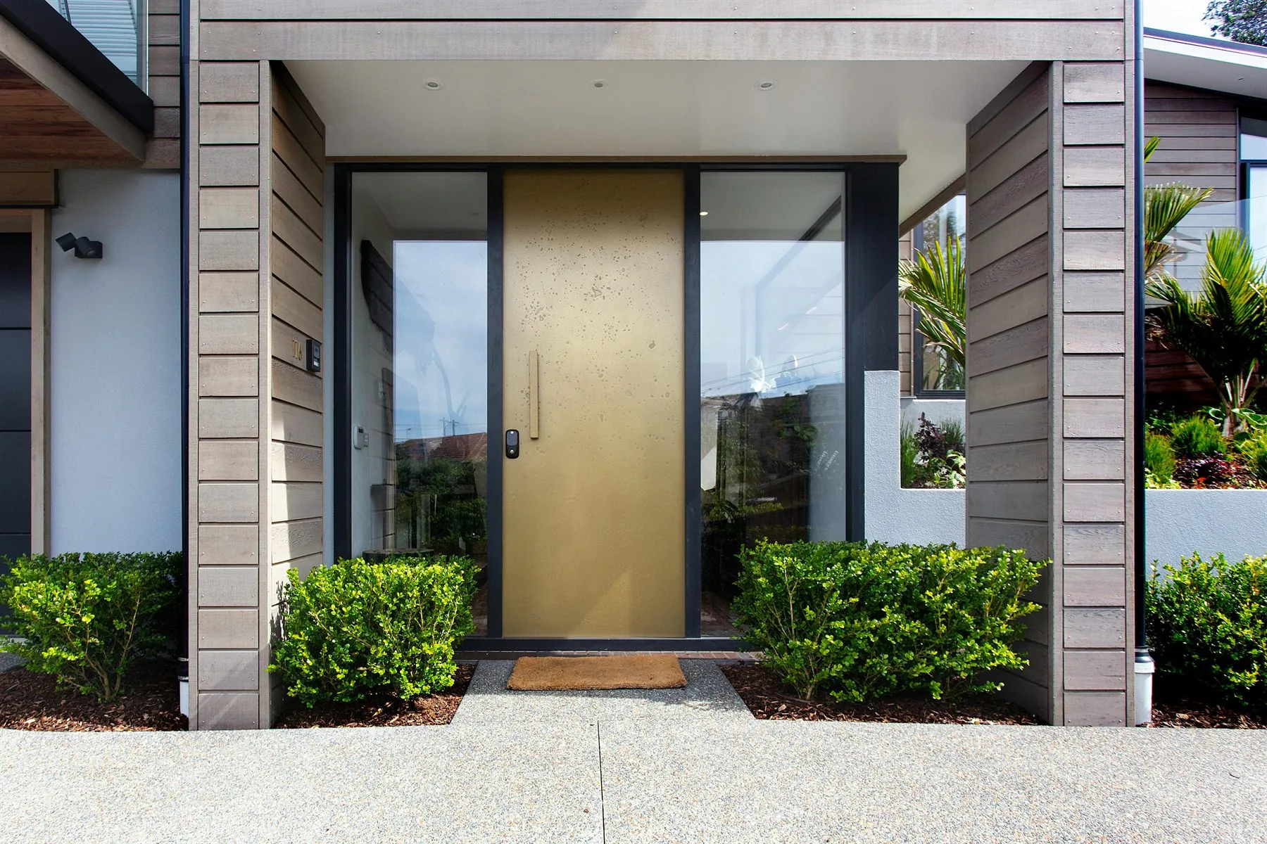 Modern home entrance with balanced landscaping and a centered front door