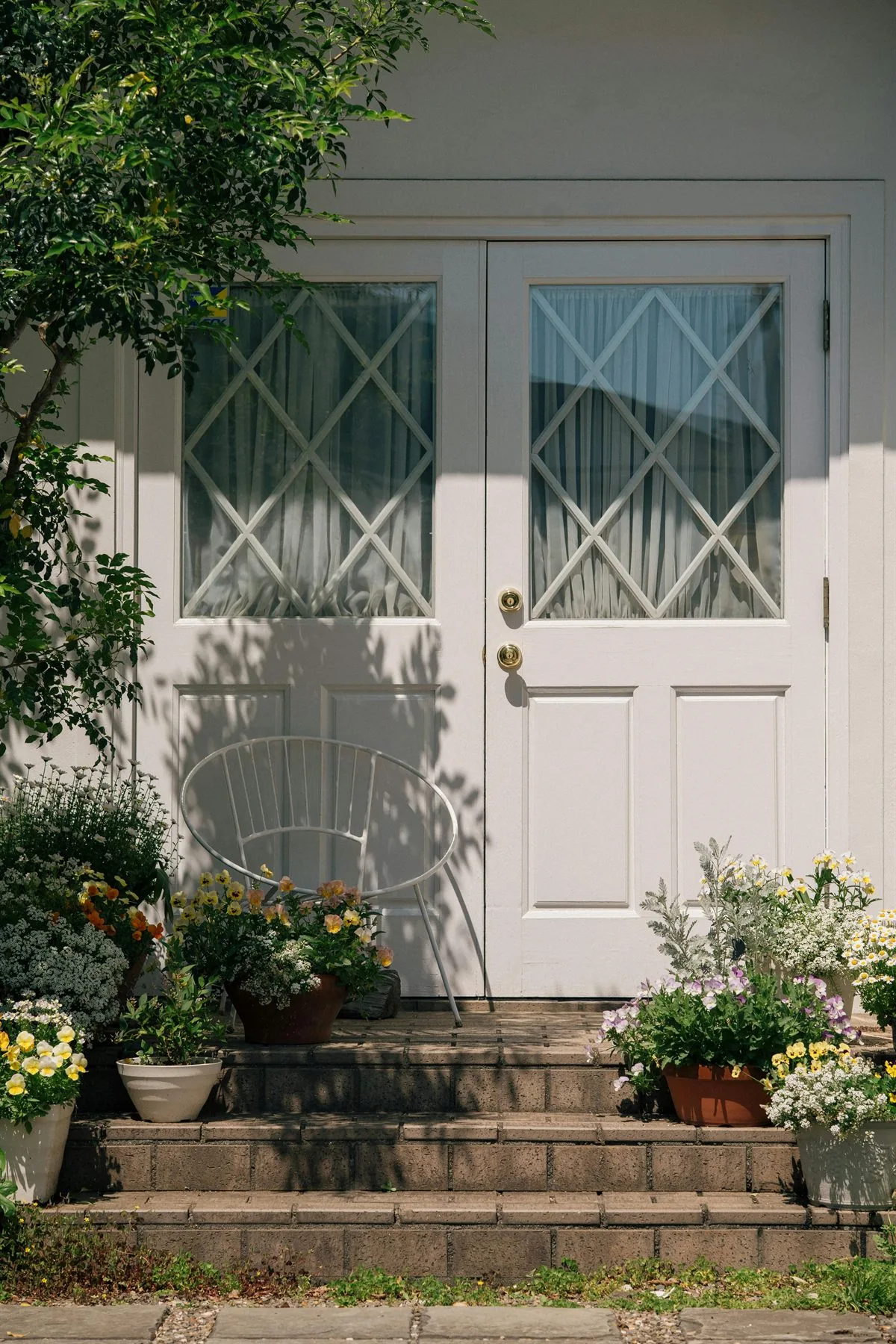 White front door with flowers in planters and a clean set of steps