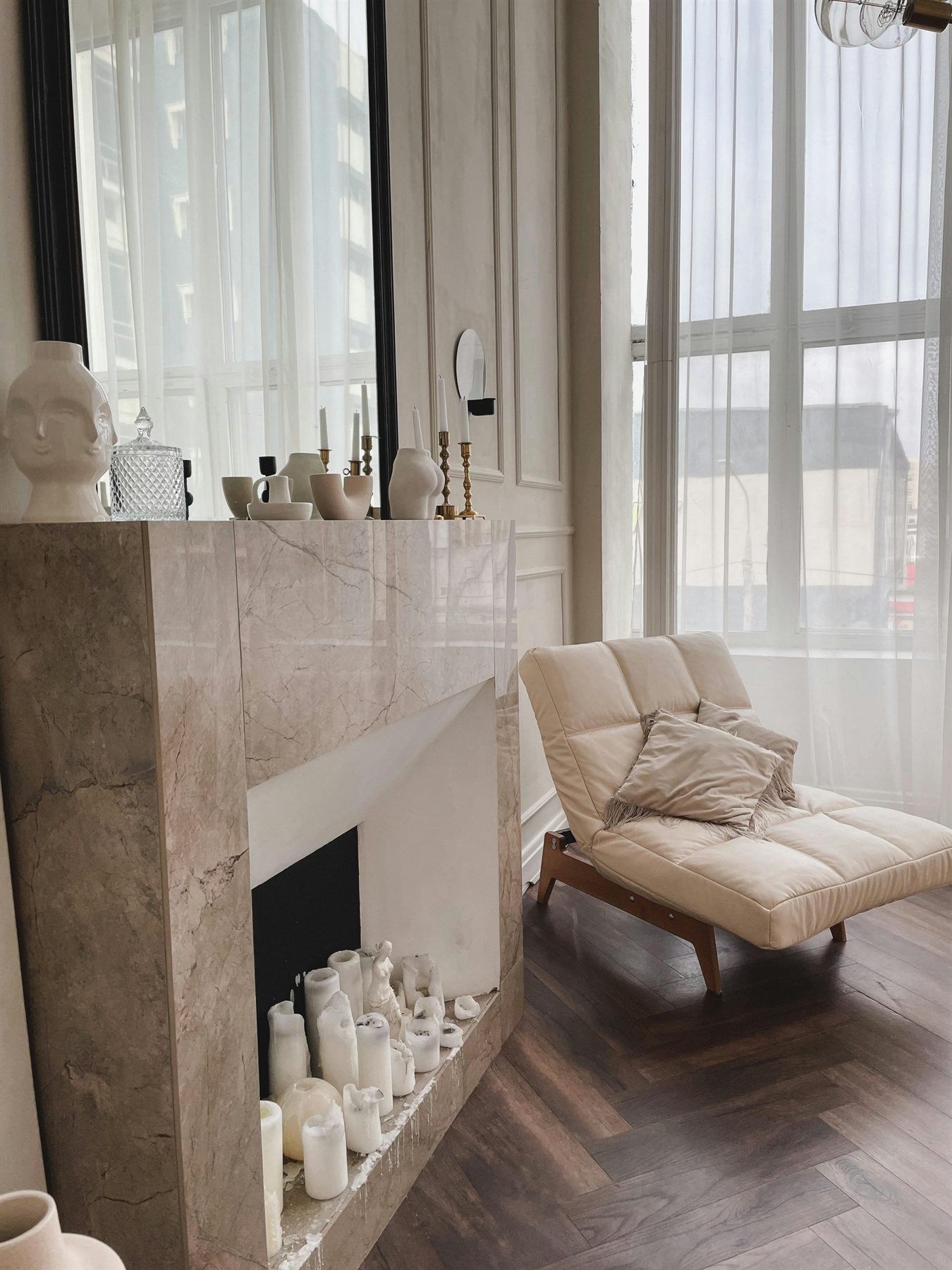 Elegant neutral room with cream chair, fireplace, and warm daylight