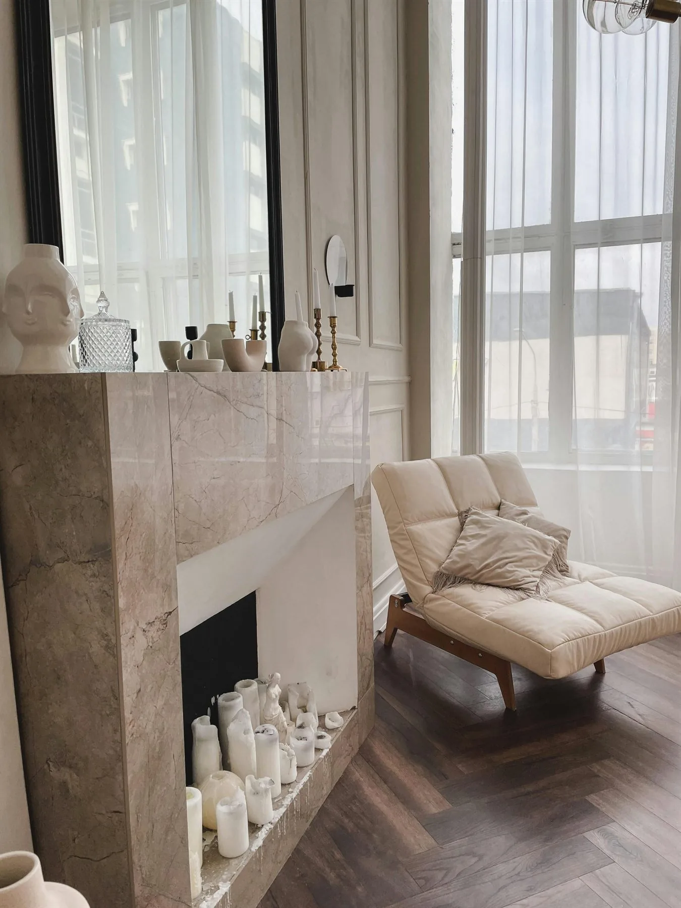 Elegant neutral room with cream chair, marble fireplace, and soft daylight