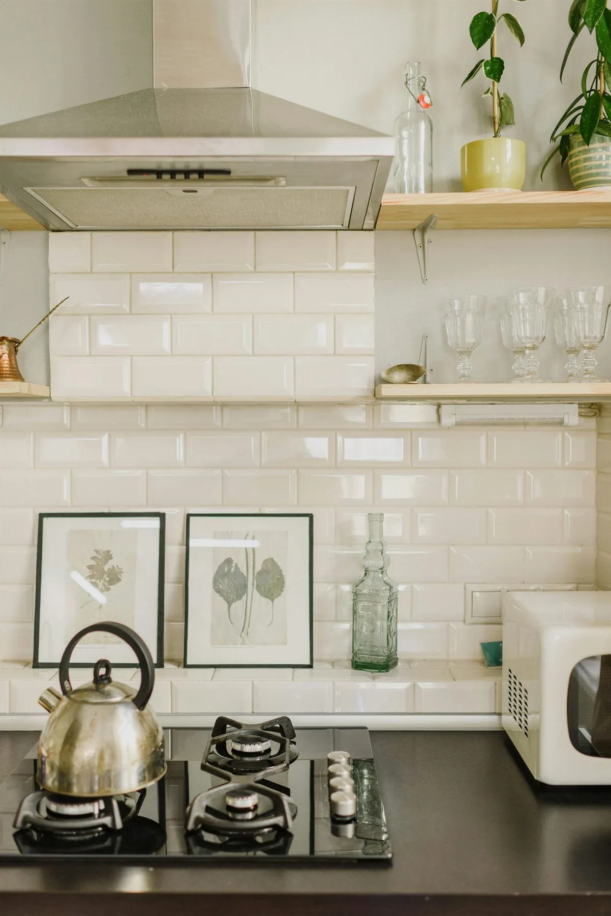 Clean kitchen with white subway tile, open shelves, and a simple kettle on the stove