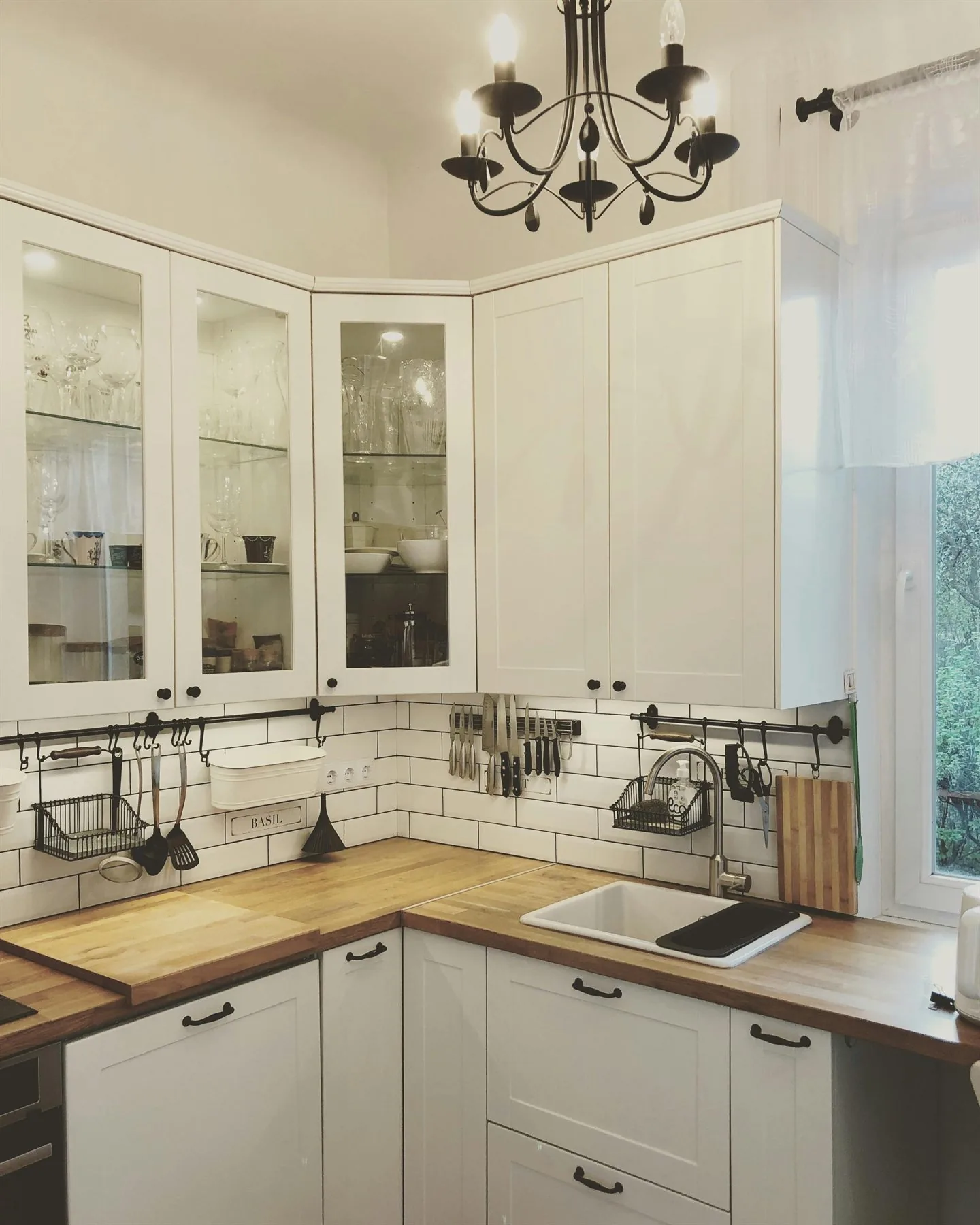 White kitchen with butcher block counters, glass-front cabinets, and softer black accents