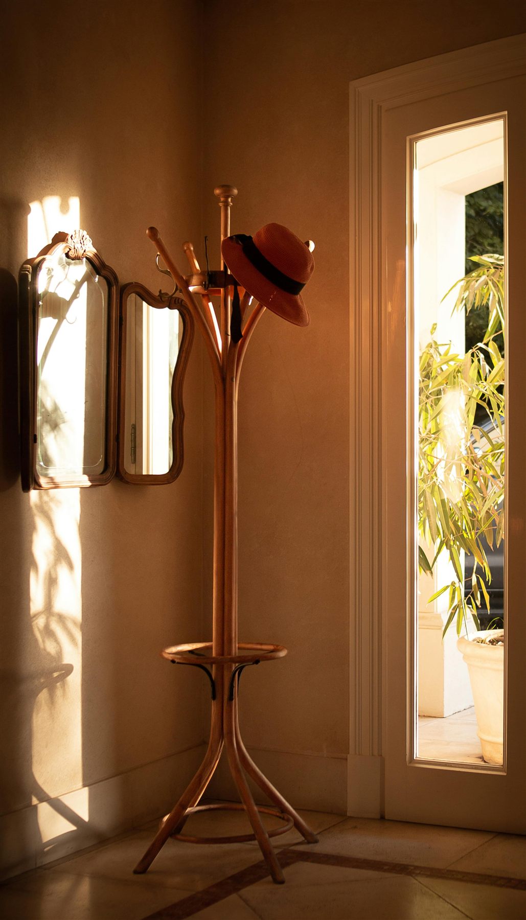 Sunlit entry corner with beige walls, a mirror, and a calm welcoming palette