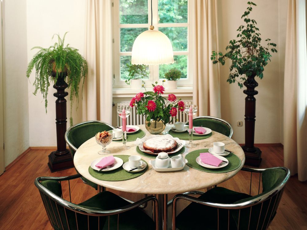 Round dining table with flowers, fruit, and warm light in a brighter room