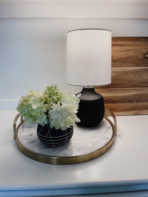 Round marble tray with a table lamp and white flowers on a clean surface