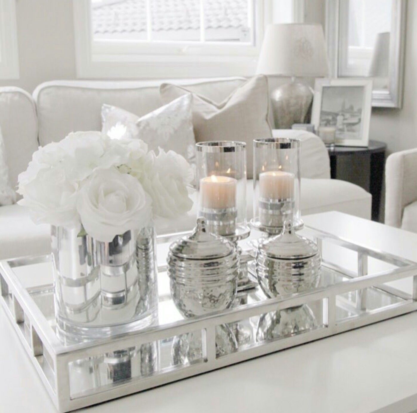 Mirrored tray with white flowers and candles on a white coffee table