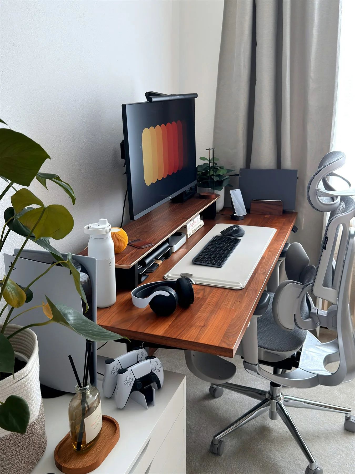 Home office desk with walnut top, gray chair, plants, and a calm neutral palette