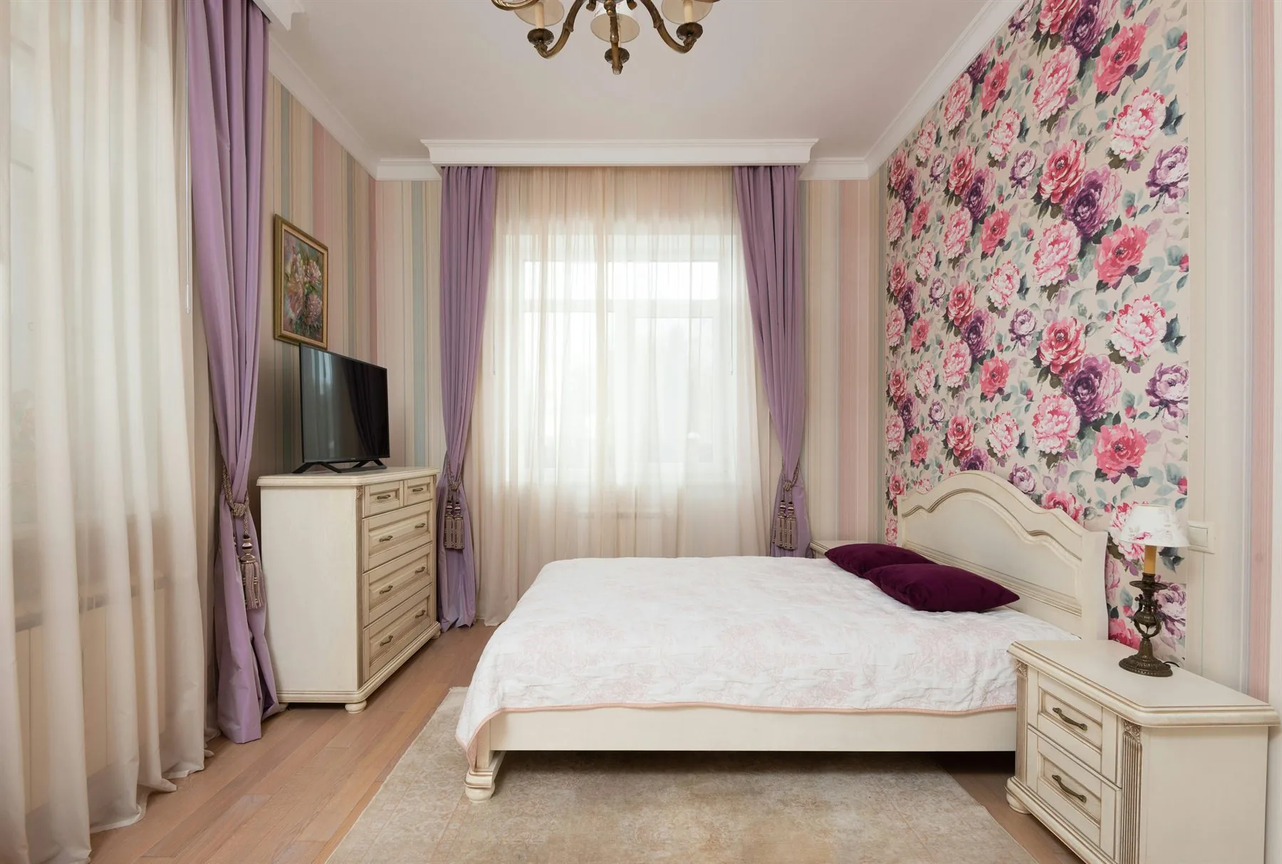 Bedroom with floral wall, lavender drapery, and a more traditional romantic palette