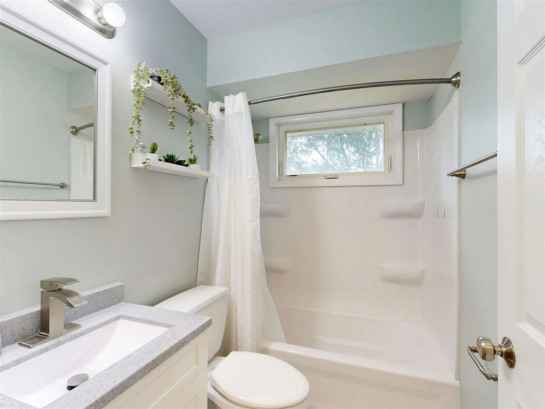 Fresh bathroom with pale sage walls, white shower curtain, and a bright clean layout
