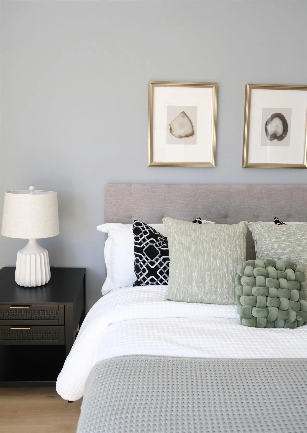 Calm bedroom with soft gray wall, white bedding, and a bedside lamp