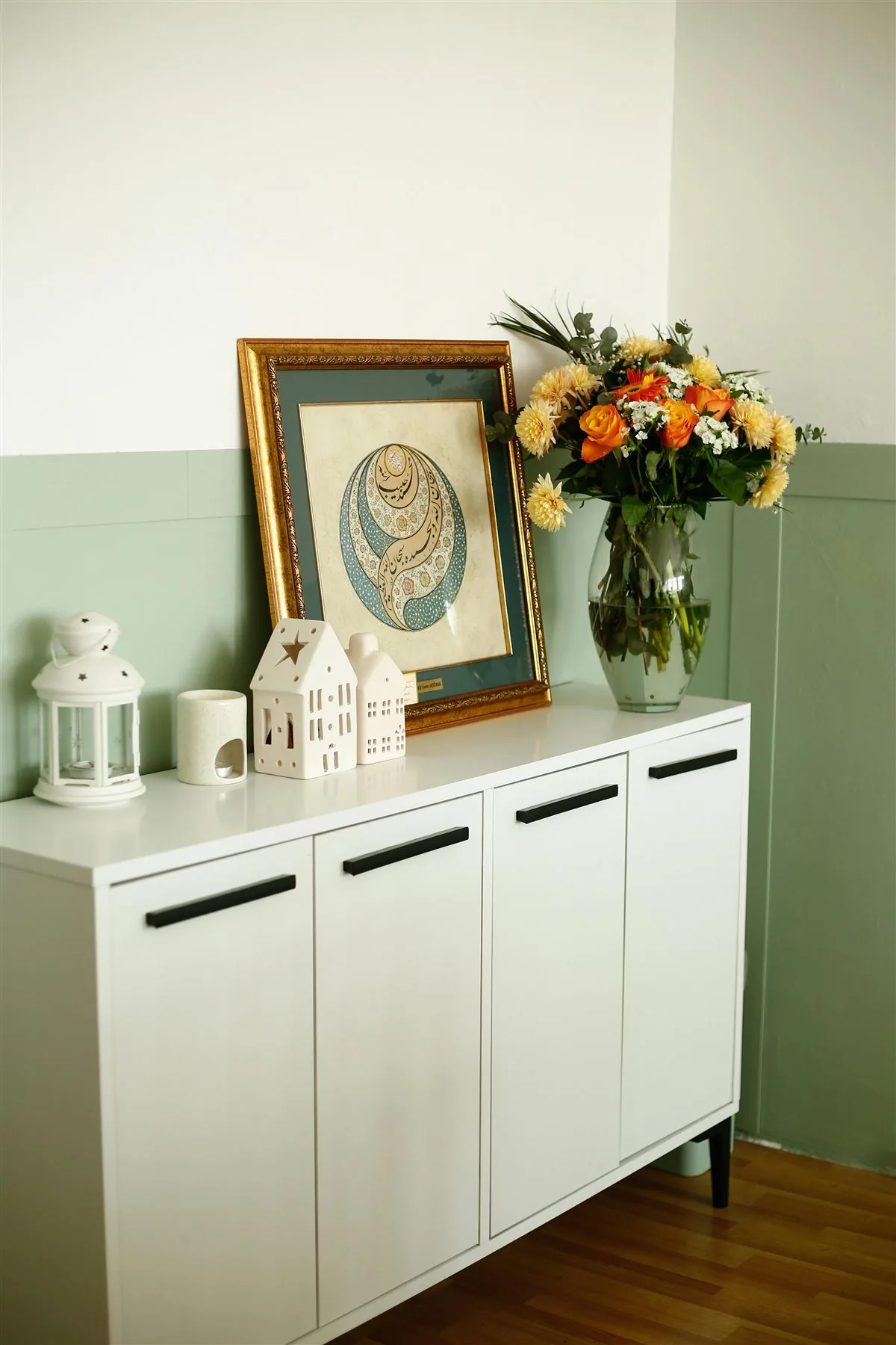 White console with framed art, flowers, and a few simple decor pieces